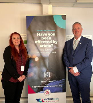 Clive Grunshaw stood next to a Victim Care Lancashire banner with female colleague
