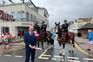 Clive Grunshaw standing in front of two mounted officers