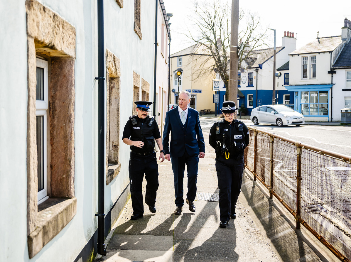 Clive Grunshaw walking with two Police Officers